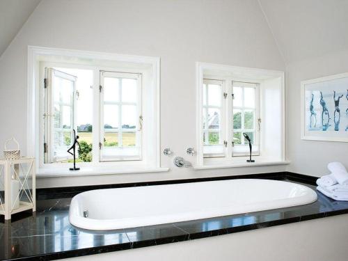 una grande vasca da bagno bianca in una stanza con finestre di Haus-zum-Leuchtturm a Kampen