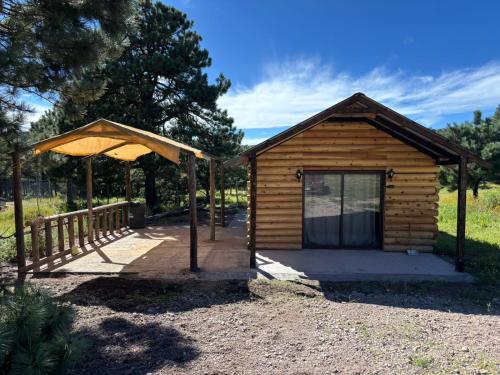 a small wooden shed with a canopy next to a fence at Cabañas La Esperanza in Creel