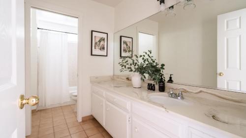 a white bathroom with a sink and a mirror at Clementine By AvantStay Bright Modern Retreat w Pool Pool Table Large Patio in Santa Rosa
