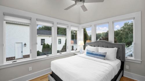 a bedroom with windows and a bed with white sheets at Sip Sip Away by AvantStay Pool Hot Tub in Westport