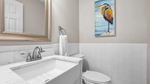 a bathroom with a toilet and a bird painting on the wall at Sip Sip Away by AvantStay Pool Hot Tub in Westport