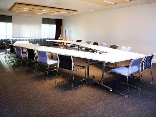 a conference room with a long table and chairs at Novotel Paris Rueil Malmaison in Rueil-Malmaison