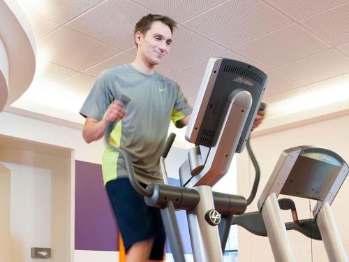 a man exercising on a treadmill in a gym at Novotel Paris Rueil Malmaison in Rueil-Malmaison