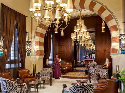 a woman standing in a lobby with chairs and a chandelier at Sofitel Legend Old Cataract in Aswan