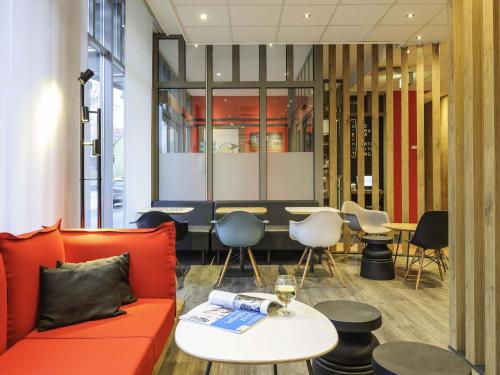 a waiting room with a red couch and tables and chairs at ibis Hotel Erfurt Altstadt in Erfurt