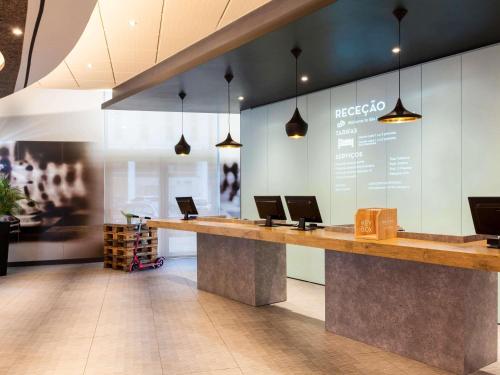 a lobby with two laptops on a long counter at Hotel ibis Lisboa Jose Malhoa in Lisbon