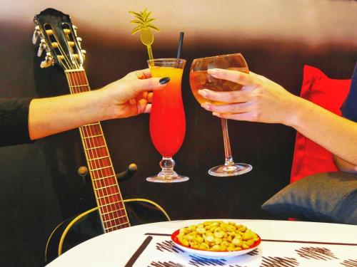 two people holding cocktails and a bowl of food and a guitar at ibis Falaise Coeur de Normandie in Falaise
