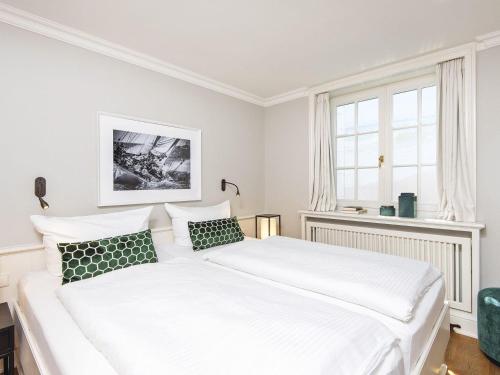 a white bedroom with a large white bed with green pillows at Hansenhoog-3 in Kampen