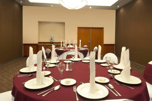 a conference room with a long table with plates and silverware at Fiesta Inn Poza Rica in Poza Rica de Hidalgo