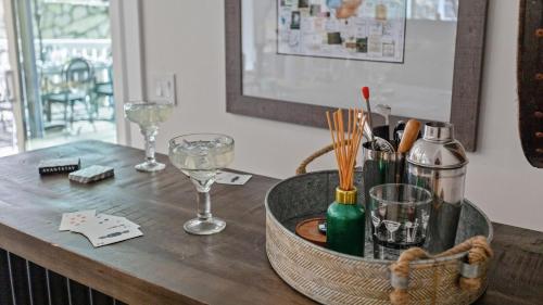 a table with a basket with wine glasses on it at Hidden Oaks Farmhouse by AvantStay Hot Tub Deck in Atascadero