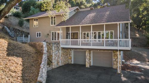 a house with a balcony and two garage doors at Hidden Oaks Farmhouse by AvantStay Hot Tub Deck in Atascadero