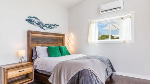 a bedroom with a bed with green pillows and a window at Chateau Coho by AvantStay Easy Beach Access in Greenbank