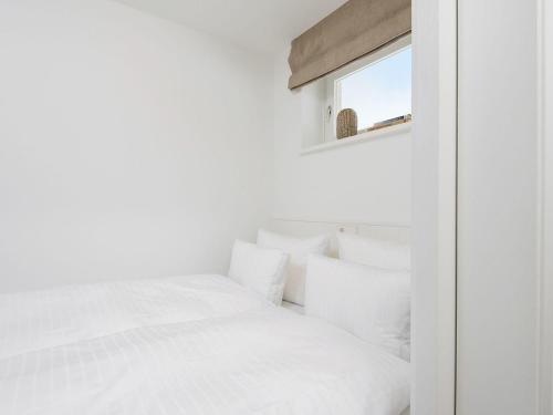 a white bedroom with a bed and a window at Kliffsand-3 in Kampen