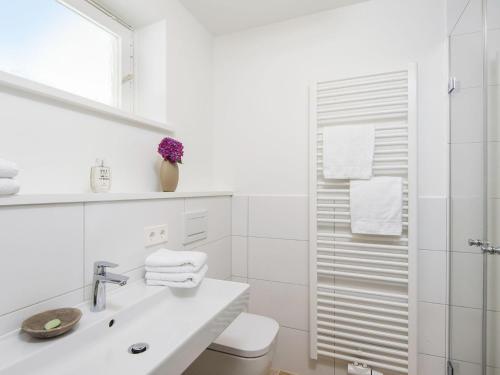 a white bathroom with a sink and a shower at Kliffsand-3 in Kampen