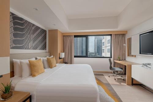 a hotel room with a large bed and a desk at Seda Bonifacio Global City in Manila