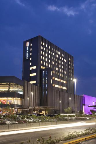 a tall black building with lights in front of a street at Fiesta Inn Parque Puebla in Puebla