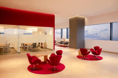 a living room with red chairs and a dining room at Fiesta Inn Parque Puebla in Puebla