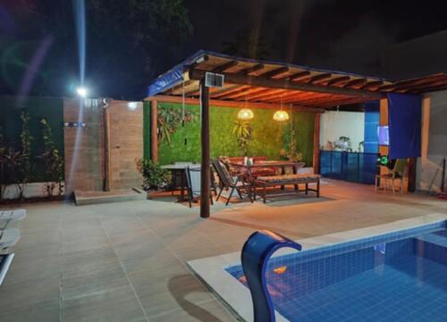 a patio with a table and a swimming pool at night at Casa Primavera aluguel temporada in Paripueira