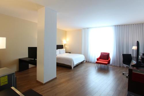 a hotel room with a bed and a red chair at Fiesta Inn Express Perinorte in Mexico City
