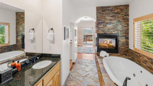 ein Bad mit einer Badewanne und einem Kamin in der Unterkunft Hot Tub Fire Pit Game Room Amazing Deck Views Sky Canyon Lodge by AvantStay in Blue Jay