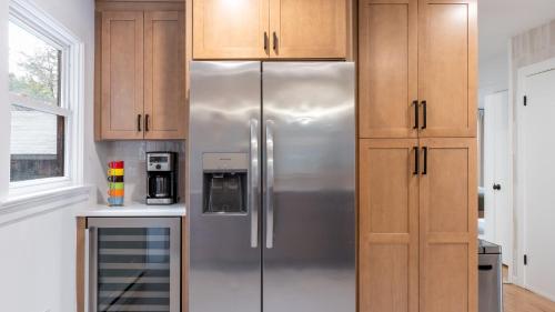 a stainless steel refrigerator in a kitchen with wooden cabinets at Charcoal Chalet by AvantStay A Design w Firepit in New Paltz