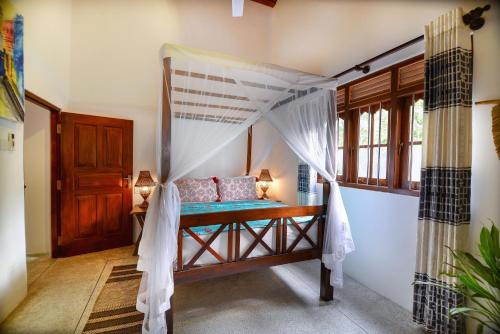 a bedroom with a bed with a canopy at Onadi House in Galle