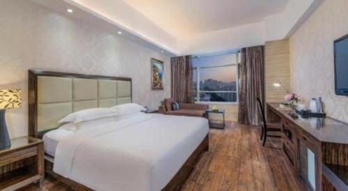 a bedroom with a large white bed and a desk at Fuzhou Xin Zi Yang Hotel in Fuzhou