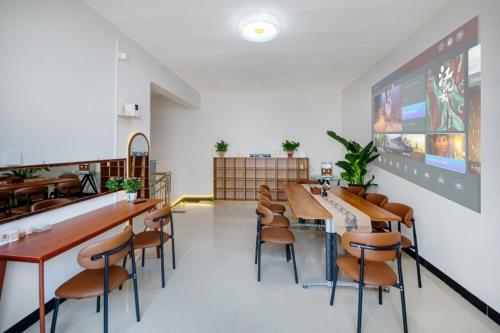 Un restaurante con mesas y sillas y una pantalla grande. en Qianxun Jushe B&B, en Kaifeng