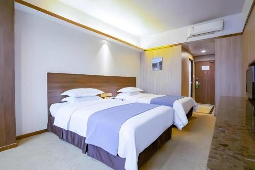 a hotel room with two beds with white sheets at My Pleasant Hotel in Shenzhen