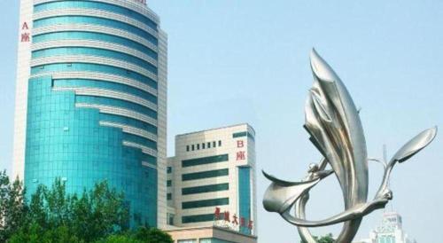 a large building with a metal sculpture in front of it at Jincheng Pacific Hotel in Jincheng