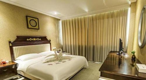 a hotel room with a large bed and a desk at Jincheng Pacific Hotel in Jincheng