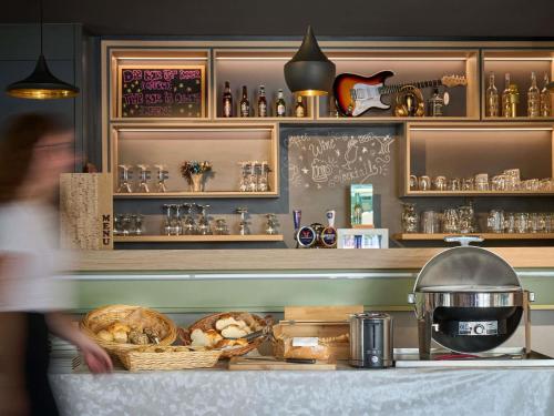 a person walking past a counter in a kitchen with food at ibis Chur in Chur