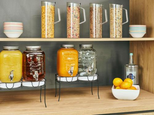 a shelf with jars of orange juice and a bowl of oranges at ibis Chur in Chur