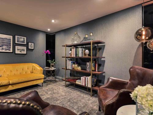 a living room with a yellow couch and a book shelf at Mövenpick Hotel Auckland in Auckland