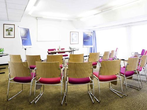 a room with a group of chairs and tables at Novotel Genova City in Genova