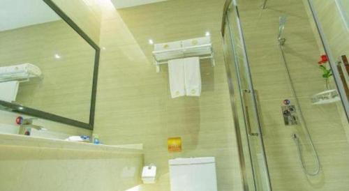 a bathroom with a shower and a toilet and towels at Auspicious Hotel in Zhongshan