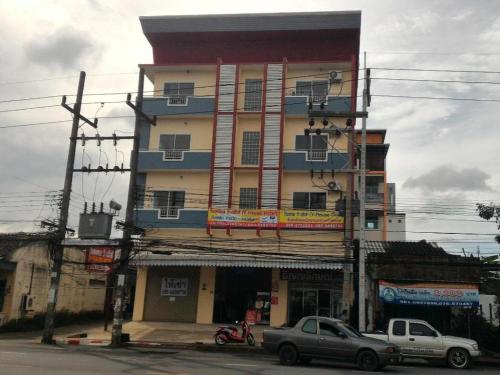 a tall building with cars parked in front of it at V-House Hotel in Trang