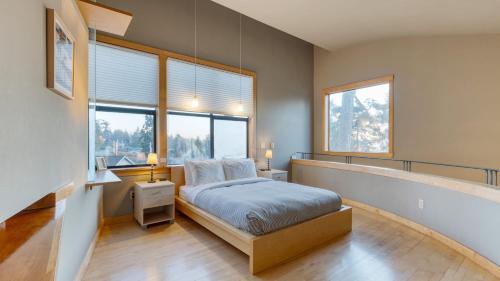 a bedroom with a bed and two windows at Deck Views Fire Pit Pool 3 Mins to Beach Madrona Tree Retreat by AvantStay in Coupeville