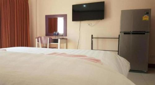 a bedroom with a bed and a television on the wall at V-House Hotel in Trang