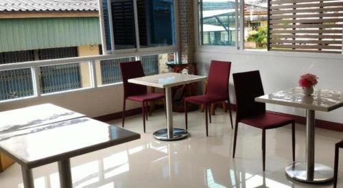 a restaurant with tables and red chairs and windows at V-House Hotel in Trang