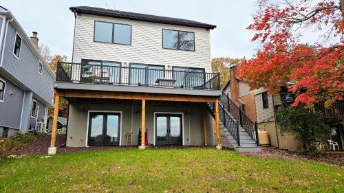 a large white house with a balcony and stairs at Lakeside Serenity by AvantStay Lakefront Newly Built Deck w Views in White Haven
