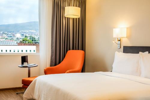 a hotel room with a bed and a chair and a window at Fiesta Inn Pachuca Gran Patio in Pachuca de Soto