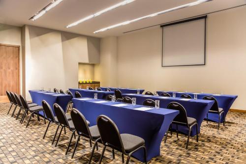 a room with blue tables and chairs and a screen at Fiesta Inn Pachuca Gran Patio in Pachuca de Soto