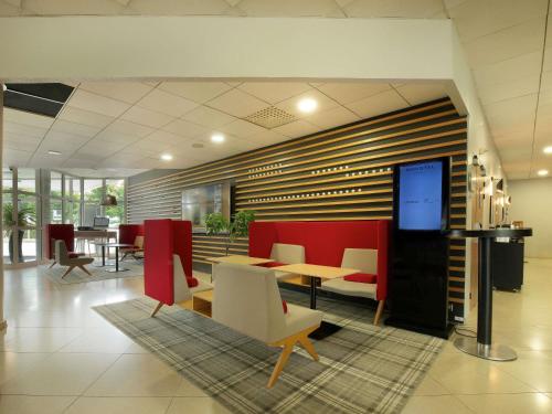 a lobby with tables and chairs and a screen at Novotel Senart Golf De Greenparc in Saint-Pierre-du-Perray