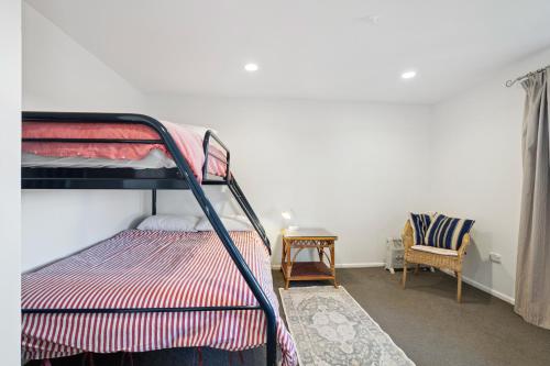 a bedroom with a bunk bed and a chair at Wanaka Central Holiday Escape in Wanaka