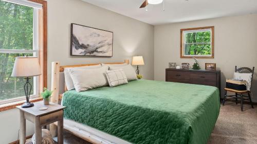 a bedroom with a bed with a green blanket at Maple Oasis by AvantStay Newly Built w Hot Tub Game Room Fire Pit in Blakeslee