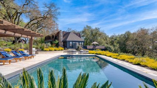 a swimming pool with chairs and a house in the background at Malvasia by AvantStay Luxe Wine Country Retreat in Santa Rosa