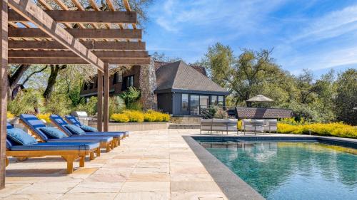 a pool with blue lounge chairs next to a house at Malvasia by AvantStay Luxe Wine Country Retreat in Santa Rosa