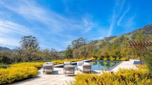 a patio with chairs and a pool with mountains in the background at Malvasia by AvantStay Luxe Wine Country Retreat in Santa Rosa