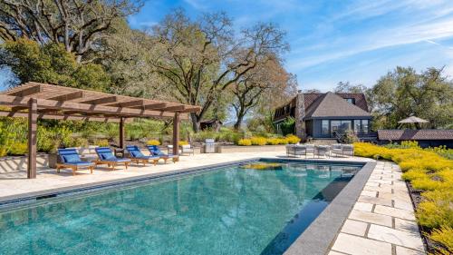 a pool with chairs and a pergola next to a house at Malvasia by AvantStay Luxe Wine Country Retreat in Santa Rosa